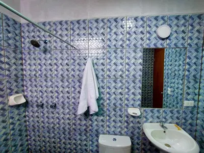 a blue tiled bathroom with a sink and a toilet at Kasanty House in Paracas