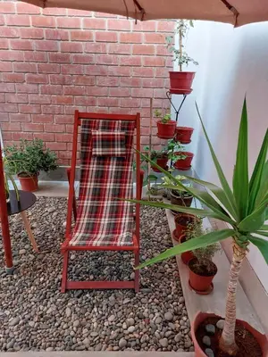 a red chair sitting next to a brick wall with plants at Kasanty House in Paracas
