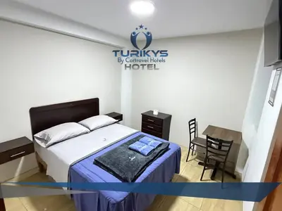 a bedroom with a bed and a table and a chair at Hotel Turikys Churin in Churín