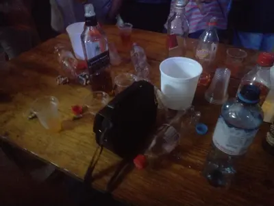 a wooden table with bottles and glasses on it at flying monkey hostel in Nazca
