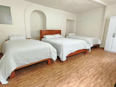 two beds in a room with white sheets at Centro Cusco Inti in Cusco