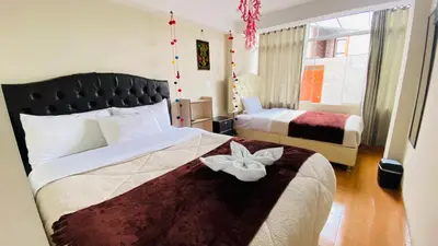 a hotel room with two beds and a flower on the bed at Hotel Valle Andino in Cusco