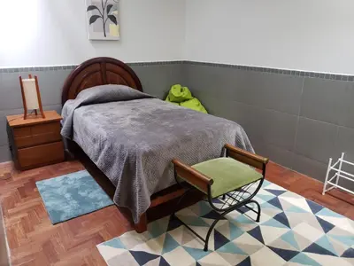 a bedroom with a bed and a chair and a rug at Amplio y Acogedor Departamento en San Miguel, Lima in Lima