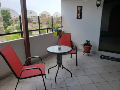 a balcony with a table and two chairs and a window at Amplio y Acogedor Departamento en San Miguel, Lima in Lima