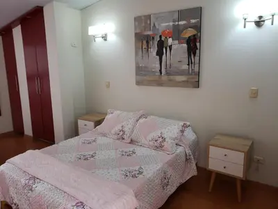 a bedroom with a bed and a painting on the wall at Amplio y Acogedor Departamento en San Miguel, Lima in Lima