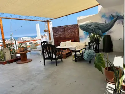 a patio with a table and chairs and a dolphin on the wall at Bravo Hostels: Surf House in Punta Hermosa