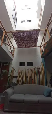 a room with a couch and surfboards on the wall at Bravo Hostels: Surf House in Punta Hermosa