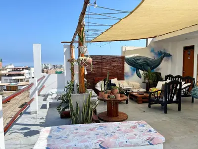 a patio with a table and chairs on a roof at Bravo Hostels: Surf House in Punta Hermosa