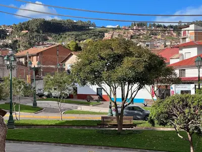 a park with a bench and a tree in a city at Hostal María Angola in Cusco