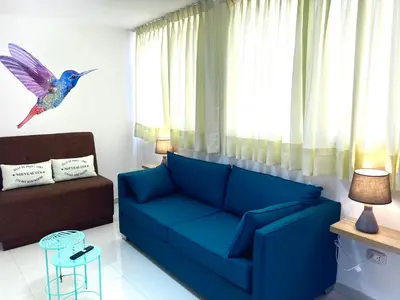 a living room with a blue couch and a bird on the wall at San Miguel, 3 dormitorios, terraza wifi cochera in Lima