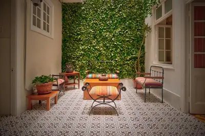 a patio with chairs and a table in front of a green wall at Casa Porta in Lima