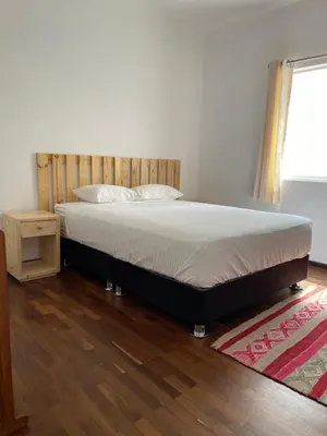 a bed in a bedroom with a wooden headboard at Casaroma Hostels in Lima