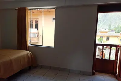 a bedroom with a window and a bed and a door at Casa D´Maria in Ollantaytambo