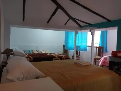 a bedroom with two beds and blue curtains at Casa D´Maria in Ollantaytambo