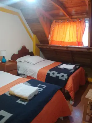 a bedroom with two beds with orange and blue blankets at hostal ollantaytambo apartments in Ollantaytambo