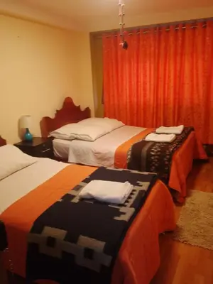 a hotel room with two beds and a window at hostal ollantaytambo apartments in Ollantaytambo