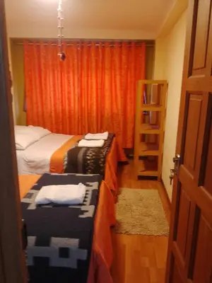a bedroom with two beds and a book shelf at hostal ollantaytambo apartments in Ollantaytambo