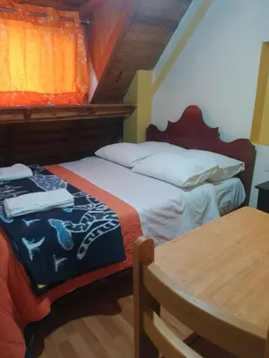 a bedroom with two beds and a table with a table at hostal ollantaytambo apartments in Ollantaytambo