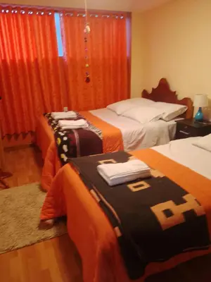a hotel room with two beds with orange sheets at hostal ollantaytambo apartments in Ollantaytambo