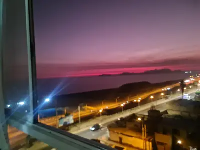 a view of a city at night from a window at Apartment 03 dormitorios San Miguel in Lima