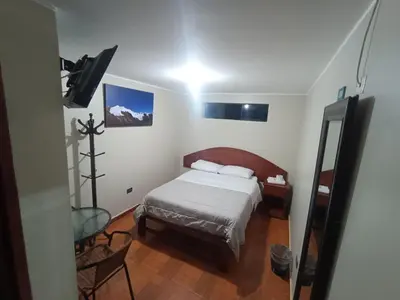 a small bedroom with a bed and a chair at HOSTAL SAMAYWASI in Huancayo