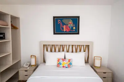 a bedroom with a white bed with two lamps and a picture at Atoq Paracas Reserva in Paracas