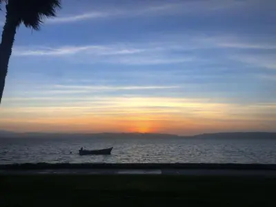a boat on the water with the sunset in the background at Atoq Paracas Reserva in Paracas