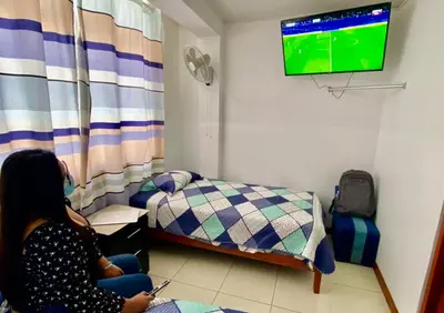 a woman sitting in a room watching a television at Hostal Venus - Nueva Imagen in Huacho