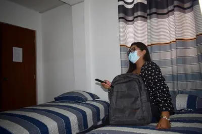 a woman wearing a mask sitting on a bed at Hostal Venus - Nueva Imagen in Huacho