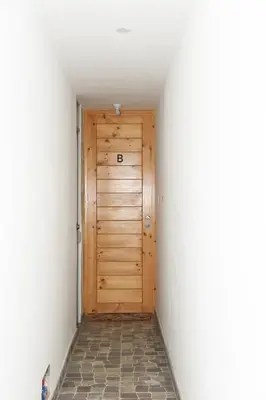a wooden door in a hallway with a tile floor at Departamento Moderno - Zona Exclusiva - Huacachina in Ica