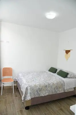 a white bedroom with a bed and a chair at Departamento Moderno - Zona Exclusiva - Huacachina in Ica