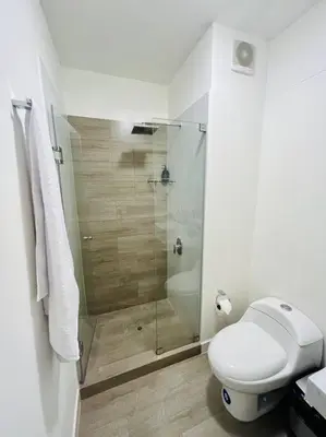 a white bathroom with a shower and a toilet at Apartment with incredible view, pool and gym in Lima