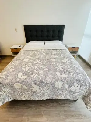 a bedroom with a bed with a gray and white comforter at Apartment with incredible view, pool and gym in Lima