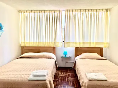 a bedroom with two beds and a window with curtains at Pershing, depa bonito, 3camas wifi/cable in Lima