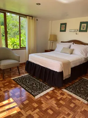 a bedroom with a bed and a chair and a window at Albergue Turístico Gstir in Pozuzo
