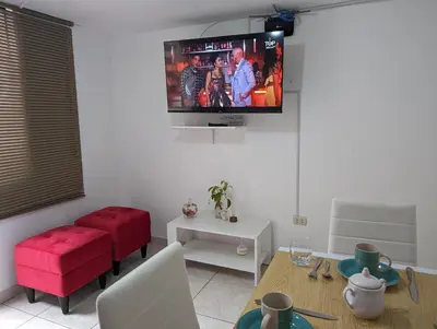 a living room with a table and a tv on the wall at Apartamento Privado, cerca al Centro Histórico de Lima in Lima