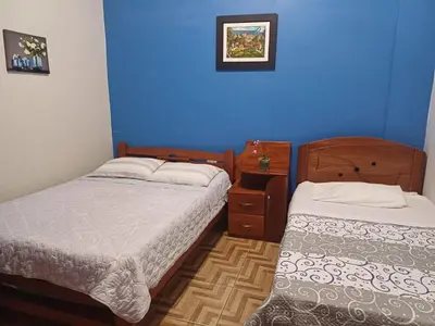 a bedroom with two beds and a blue wall at MI SELVA Y SU ENCANTO in La Merced