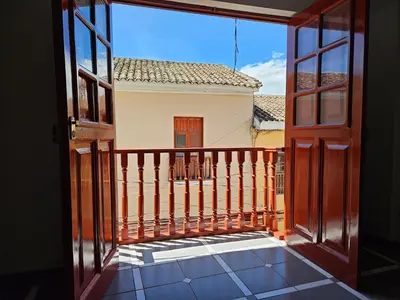 an open door to a balcony with a view of a house at COZZY APARTMENT IN AYACUCHO in Ayacucho