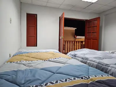 two beds sitting in a room with a window at COZZY APARTMENT IN AYACUCHO in Ayacucho