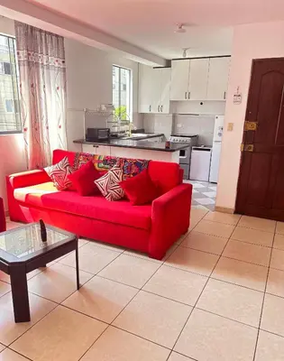 a red couch in a living room with a kitchen at Hermoso Apartamento Miraflores Central in Lima