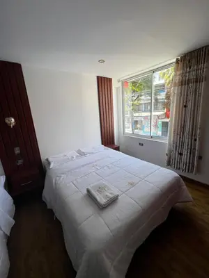 a bedroom with a large white bed with a window at Hotel SOGU TOWER in Ayacucho