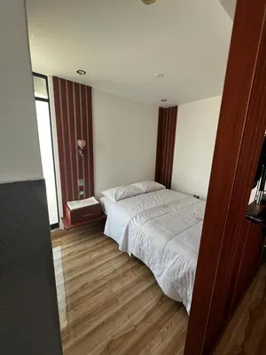 a bedroom with a white bed and a wooden floor at Hotel SOGU TOWER in Ayacucho