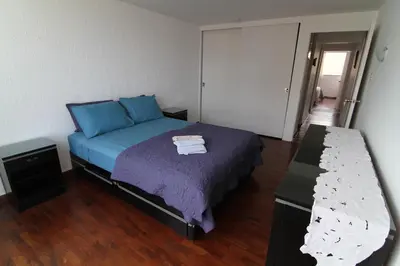 a bedroom with a bed with blue sheets and a table at The Guest House 1 at the booming center of Miraflores, Lima - Peru in Lima