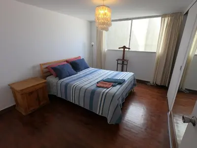 a bedroom with a bed with blue pillows and a window at The Guest House 1 at the booming center of Miraflores, Lima - Peru in Lima