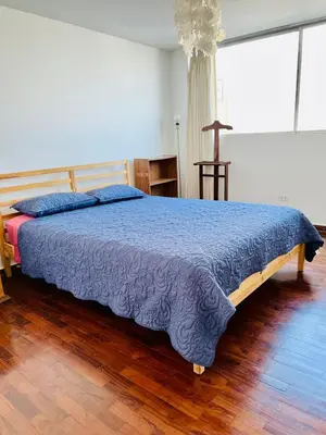 a bedroom with a large bed with a blue blanket at The Guest House 1 at the booming center of Miraflores, Lima - Peru in Lima