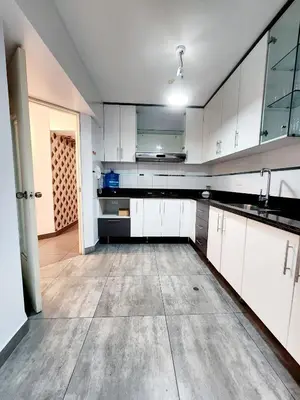 an empty kitchen with white cabinets and a wooden floor at Duplex MyM in Lima
