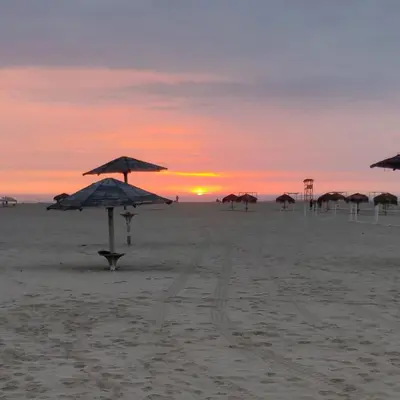 a group of umbrellas on the beach at sunset at Alquilo casa de playa Condominio Playa Azul cerca de Asia in Cerro Azul
