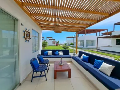 a patio with blue couches and a wooden pergola at Alquilo casa de playa Condominio Playa Azul cerca de Asia in Cerro Azul