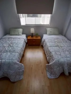 a bedroom with two beds and a table with a lamp at Miraflores View in Lima