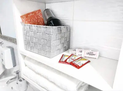 a bathroom with a shelf with towels and a bottle of wine at Hospedaje Celerina & Elio in Lima